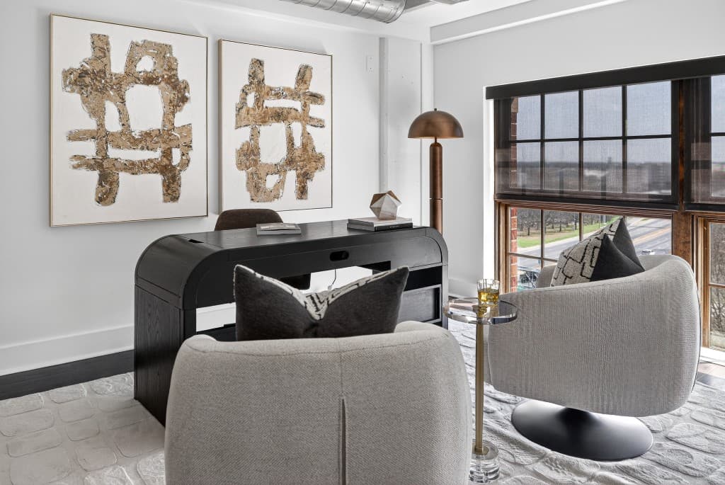 Modern home office with abstract wall art, desk, and neutral staging decor